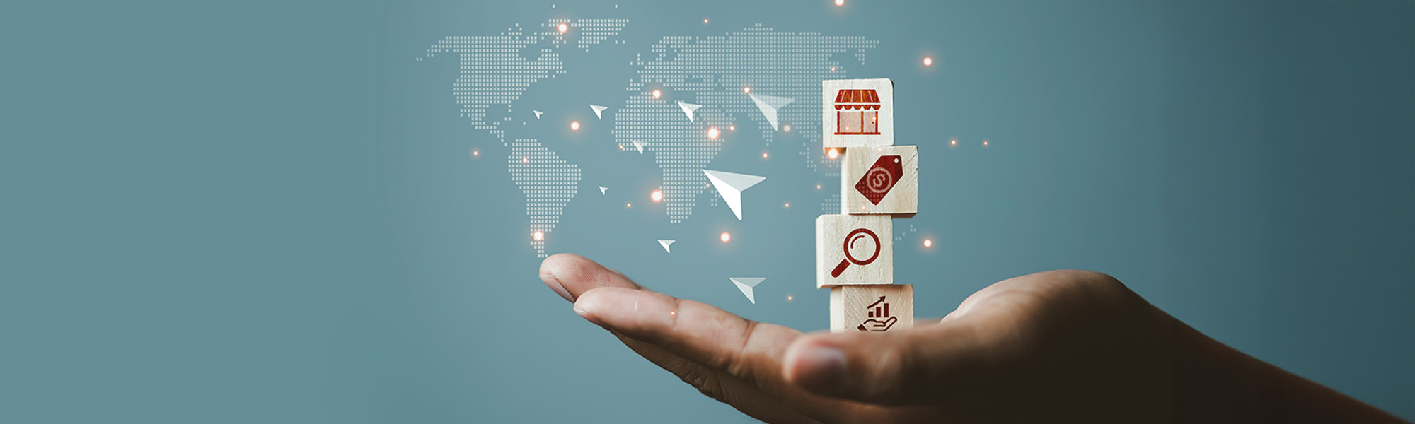 La foto mostra l'elaborazione grafica di una mano che regge una serie di icone rappresentative dei beni di consumo, sullo sfondo un planisfero e delle frecce che indicano l'export